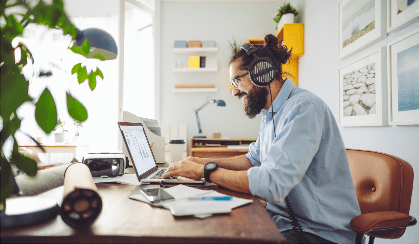 Person with beard sitting at desk typing on laptop